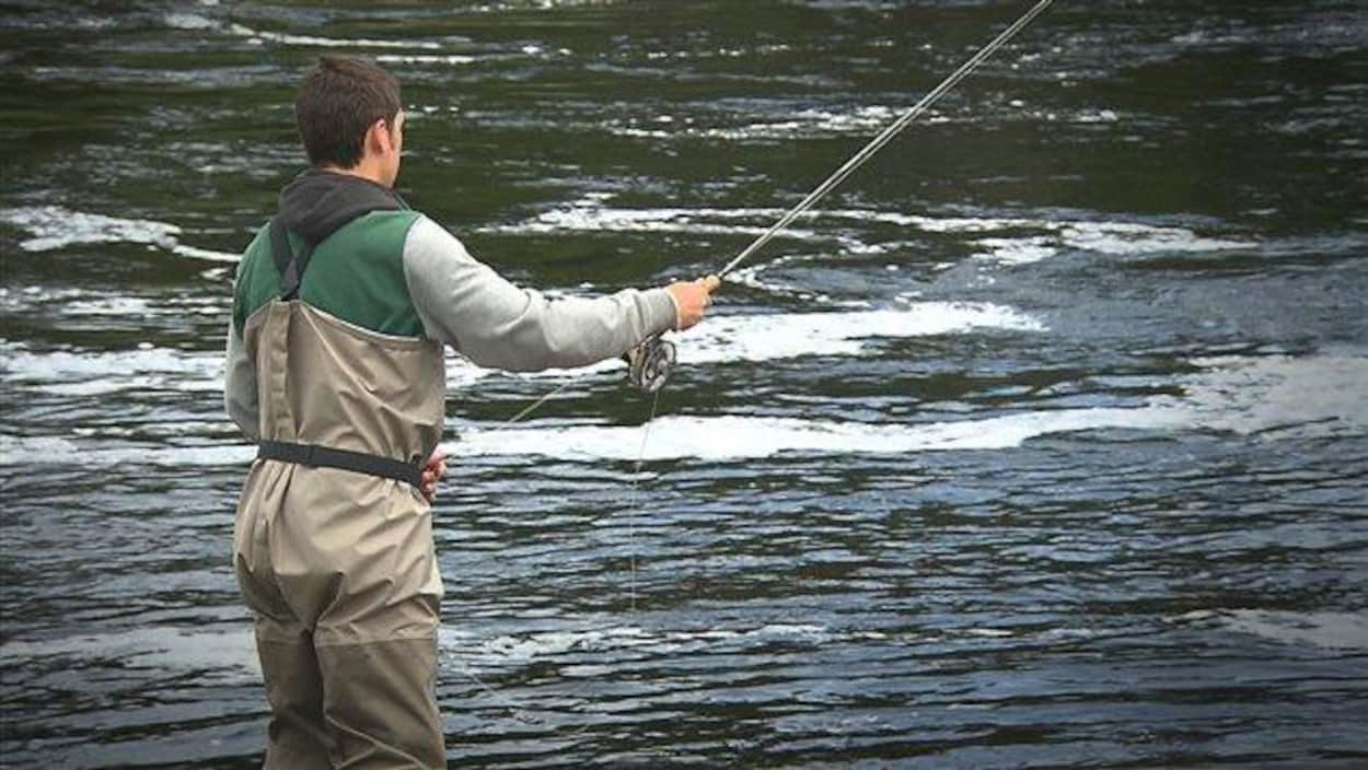 Un pêcheur à la mouche dans une rivière à saumons.