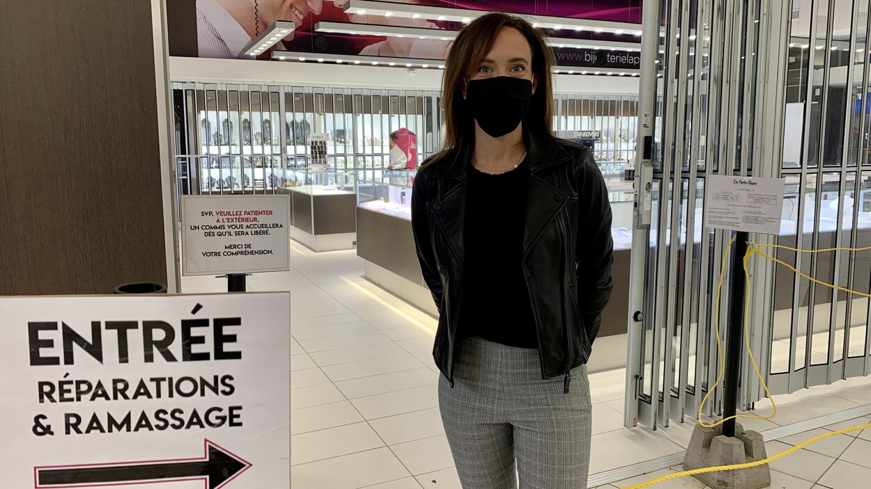 Une dame portant un masque devant une bijouterie.