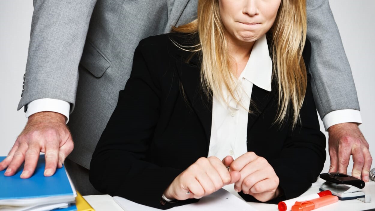 un homme se tient debout derrière une femme qui est assise à un bureau