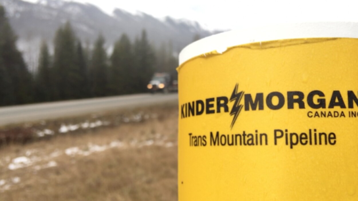 Logo de l'entreprise Kinder Morgan en premier plan, en bordure d'une route. Logo de l'entreprise Kinder Morgan en premier plan, en bordure d'une route.