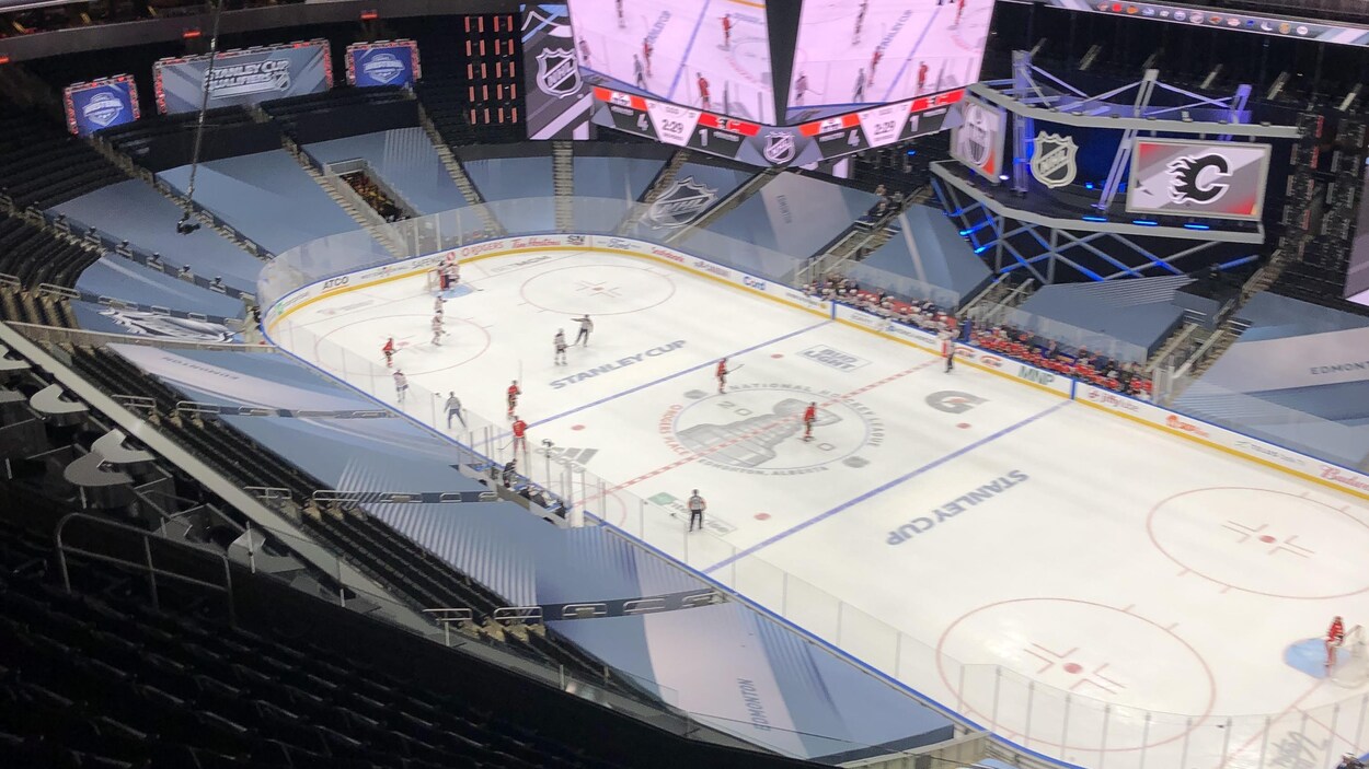 Des joueurs de hockey qui pratiquent sur la glace, sont vus en simultané sur l'écran géant de la place Rogers.