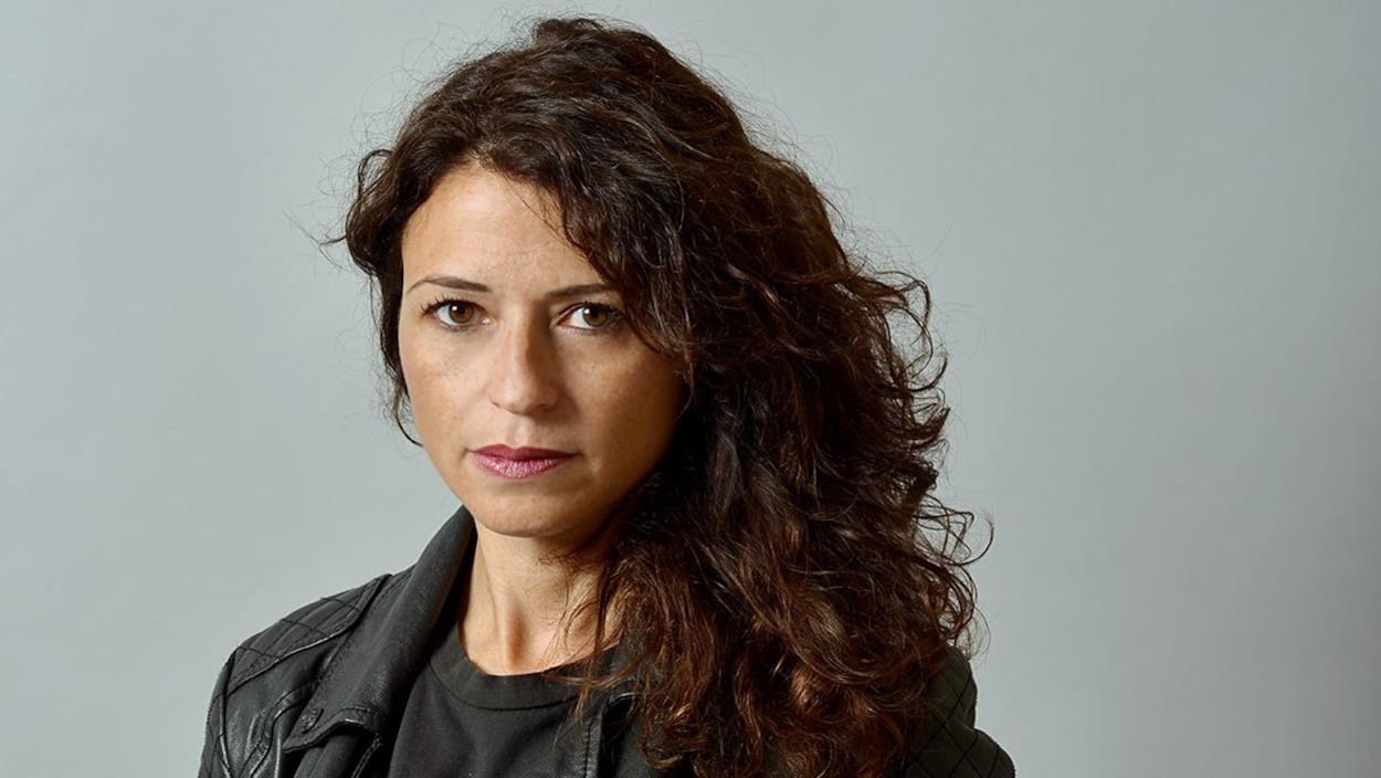 Portrait de Karine Tuil, qui porte de longs cheveux bouclés.
