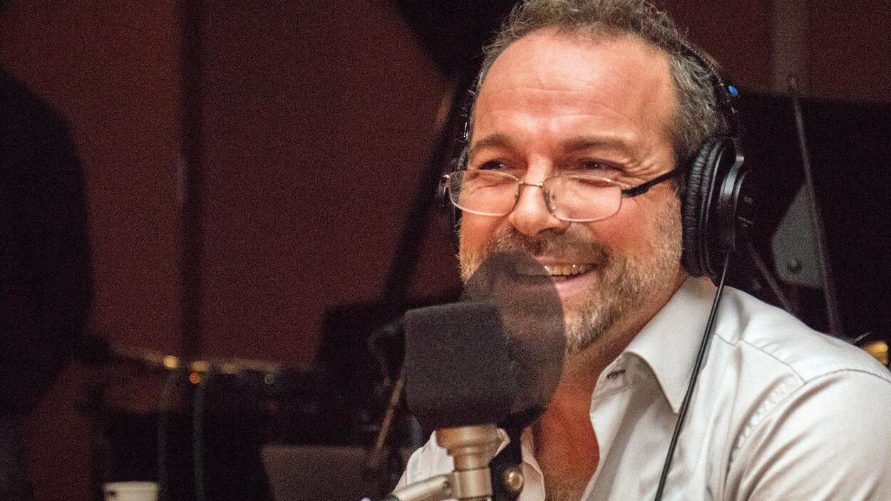 L'auteur Michel Duchesne sourit devant un micro.