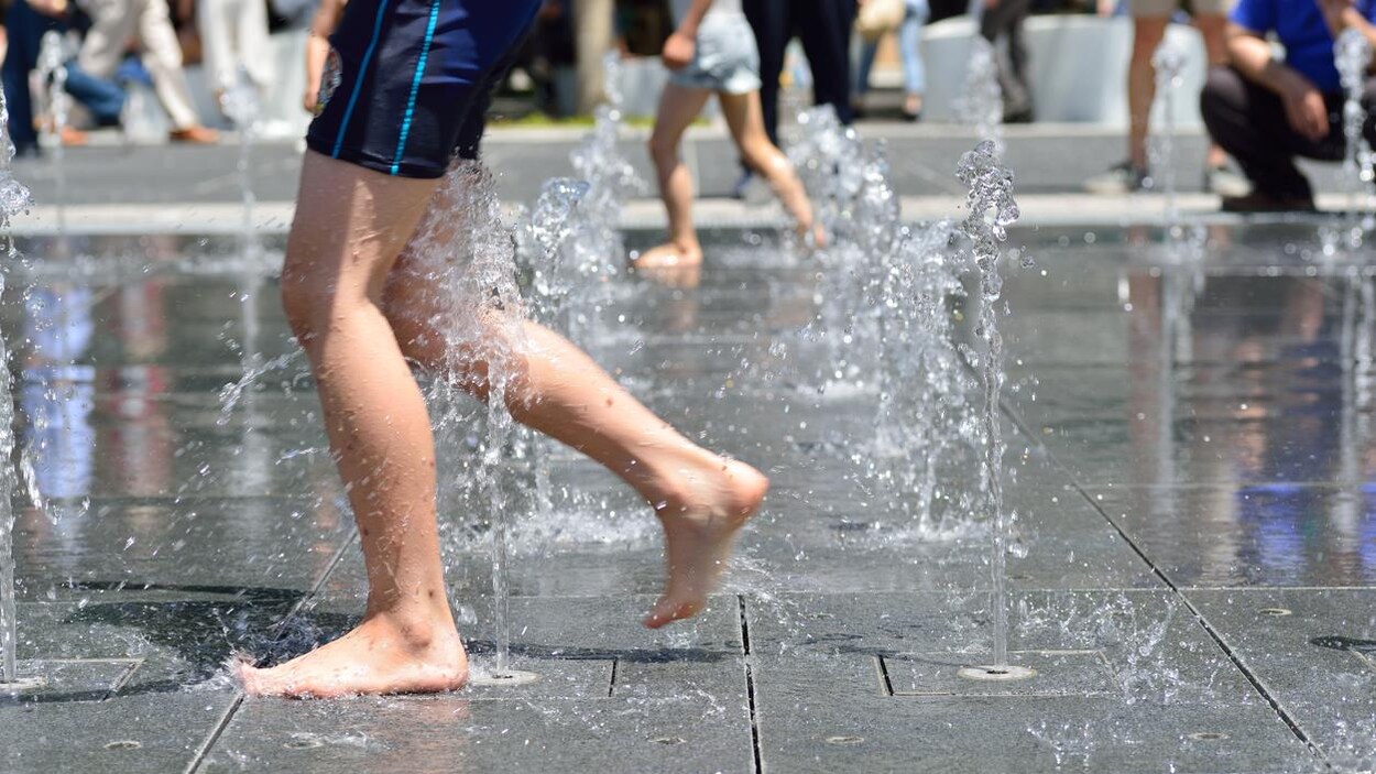 Un garçon en maillot de bain joue dans des jeux d'eau.