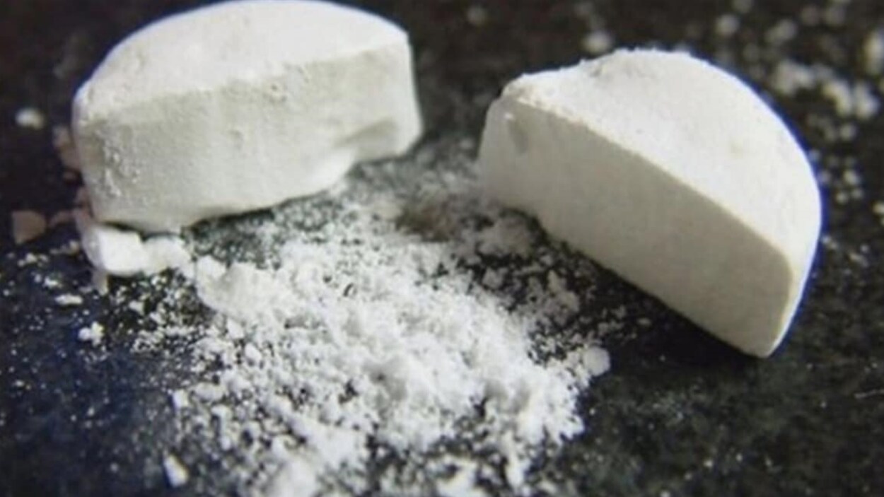 Un comprimé de drogue est coupé en deux sur une table. Un comprimé de drogue est coupé en deux sur une table.