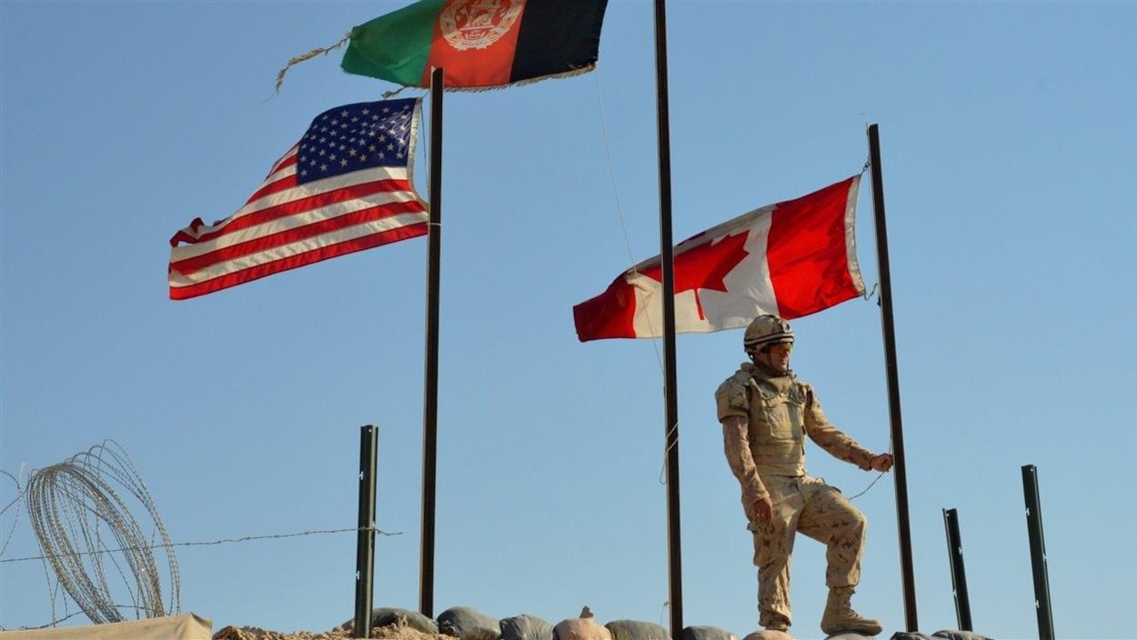 Un soldat en habit de camouflage met un drapeau en berne.