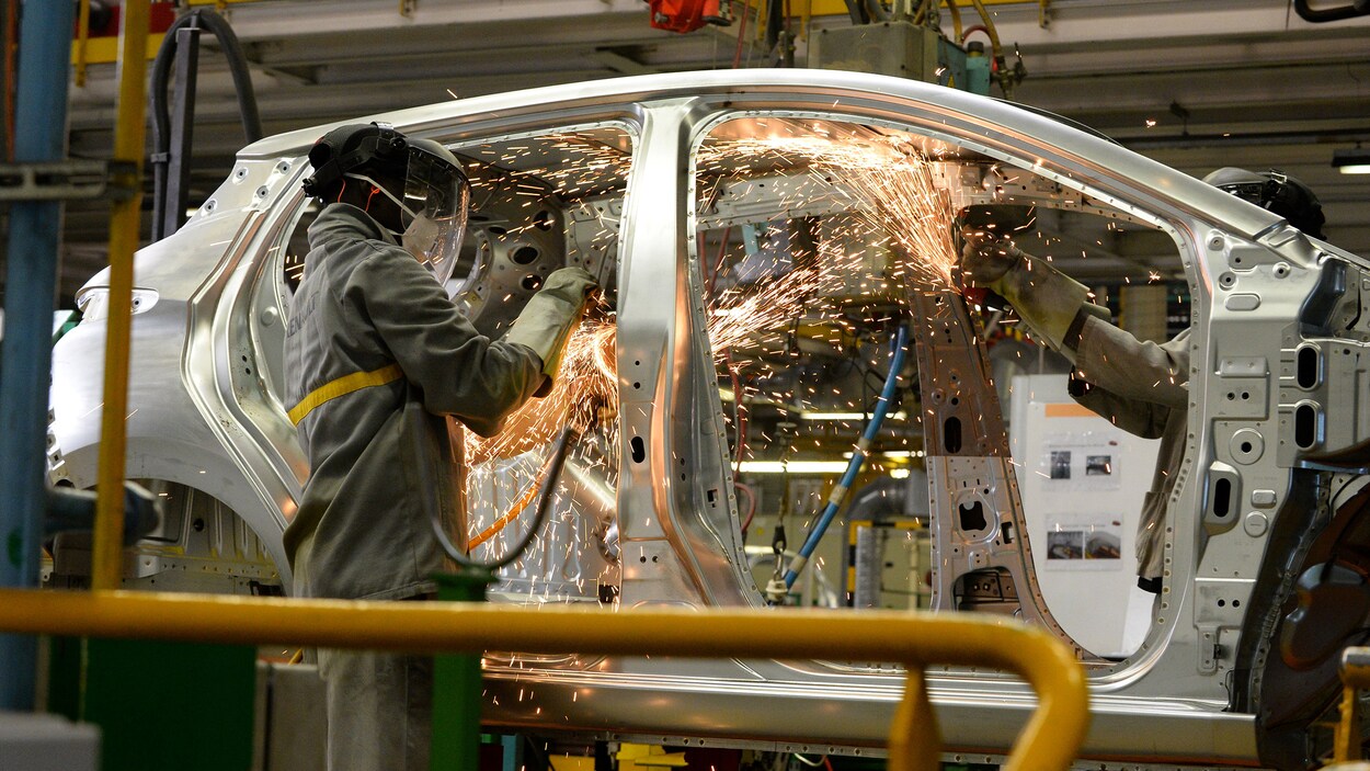 Un travailleur fait de la soudure sur la carrosserie d'une automobile.