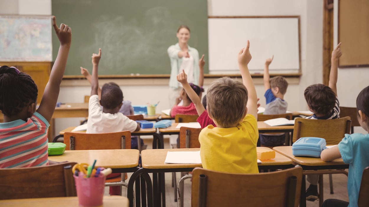 Élèves en classe qui lèvent la main avec professeur derrière. Élèves en classe qui lèvent la main avec professeur derrière.