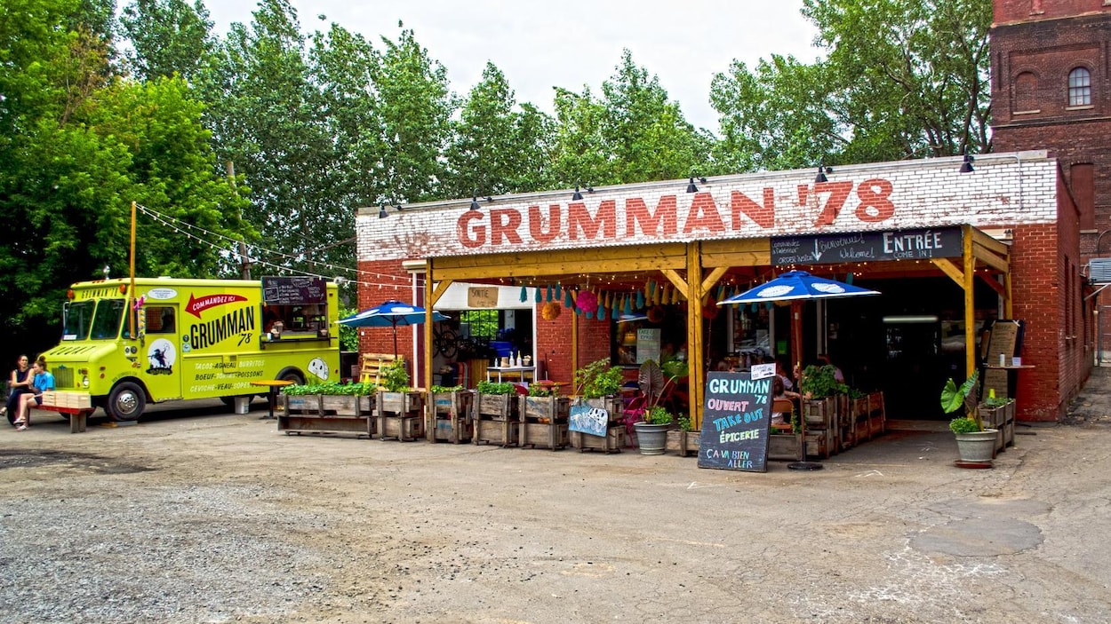 Un petit restaurant aménagé dans un garage, à côté duquel se trouve un camion de cuisine de rue.