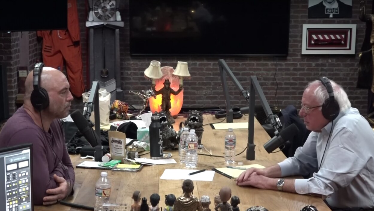 Deux hommes discutent autour d'une table dans un studio d'enregistrement.