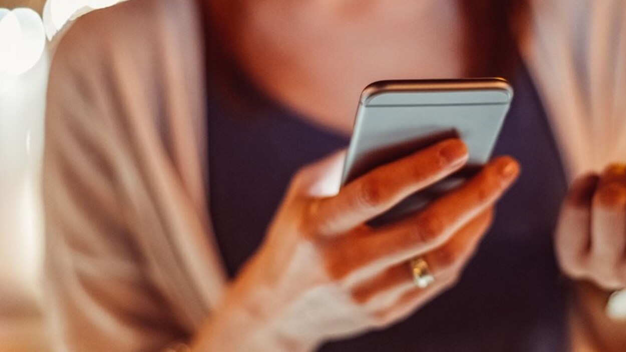 Une femme tient un cellulaire dans une main Une femme tient un cellulaire dans une main