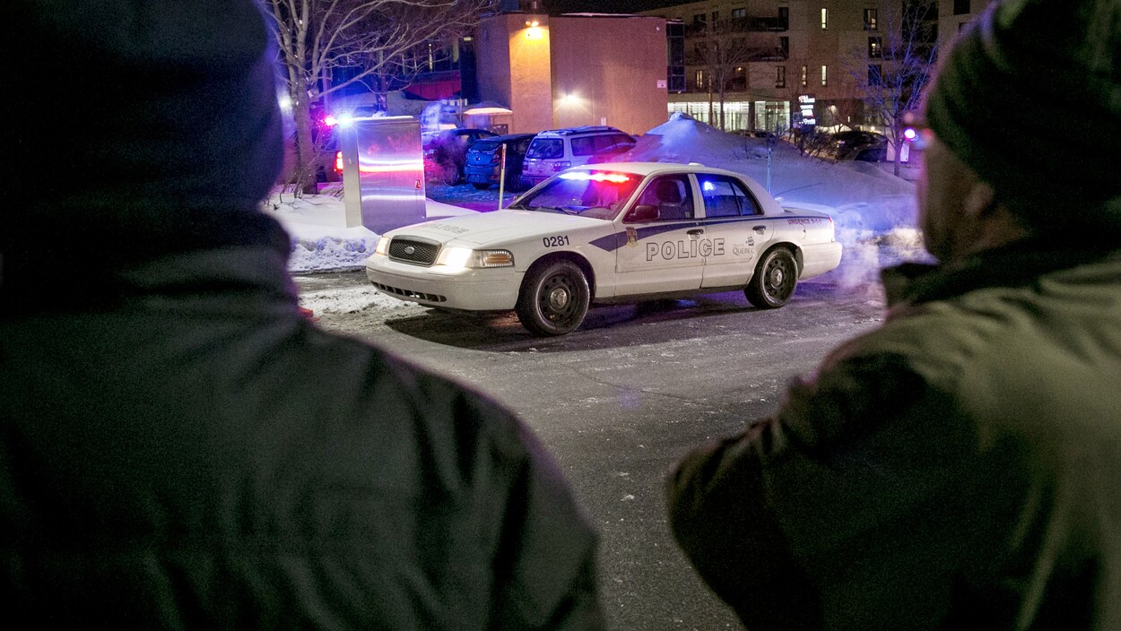 Deux hommes regardent la grande mosquée de Québec dans les instants après l’attentat.(archives)