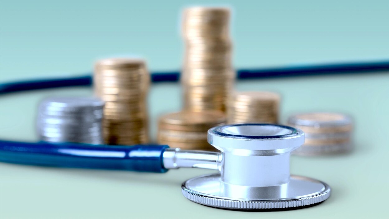 Un stéthoscope devant une pile de monnaie.