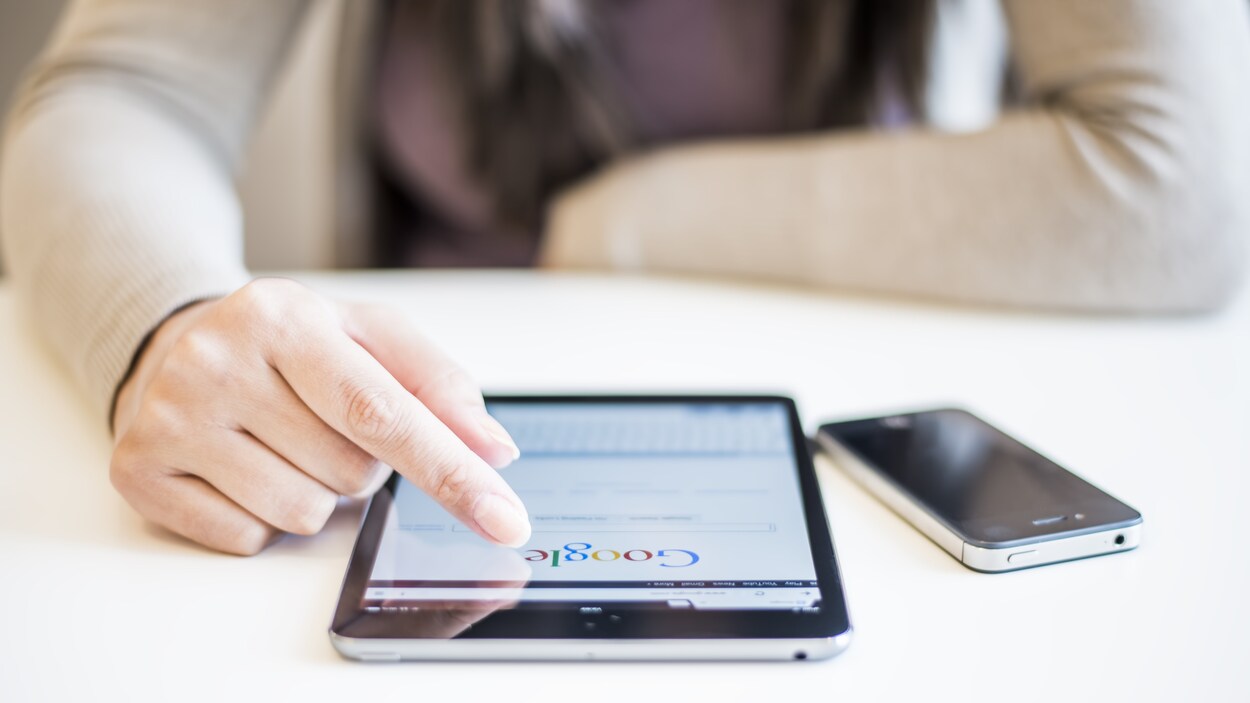 Une femme devant une tablette électronique posée sur une table.