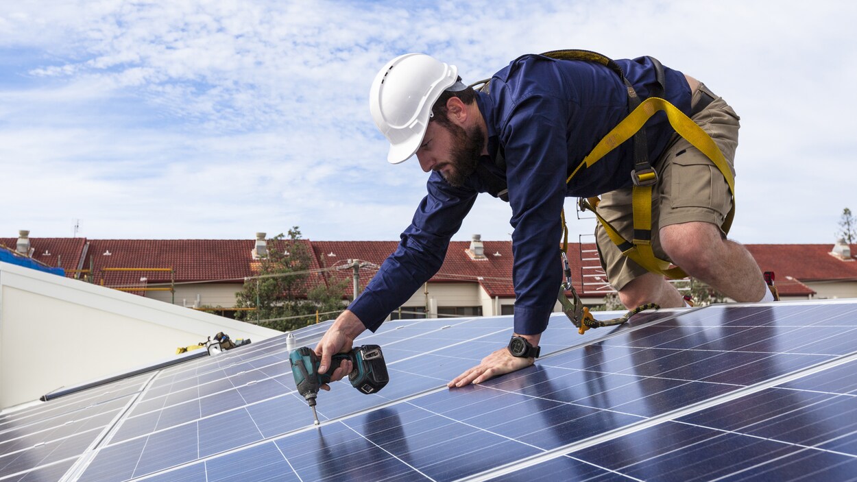 Un technicien pose des panneaux solaires.