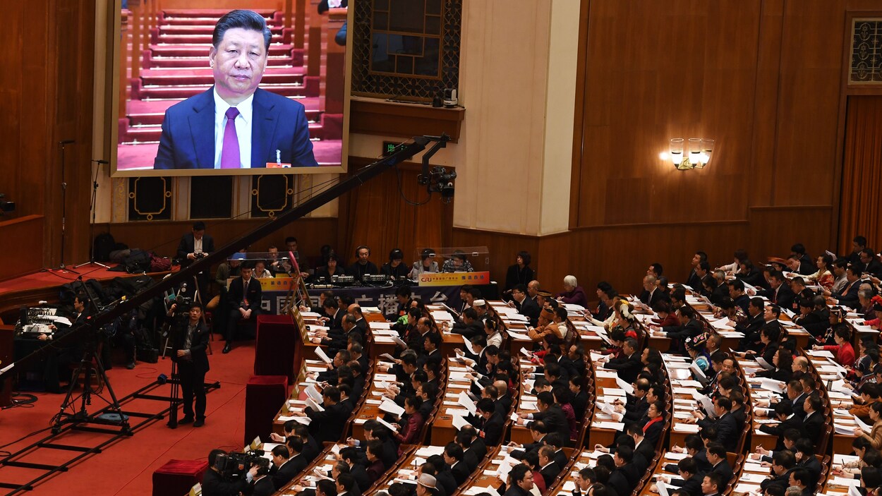 L'image du président Xi Jinping est retransmise sur grand écran devant des députés dans l'amphithéâtre du Palais du peuple, à Pékin, le 5 mars 2018.
