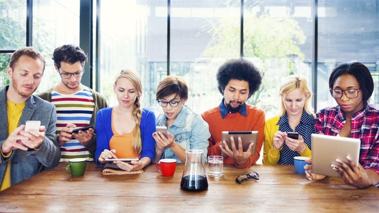 Sept jeunes ayant chacun en main une tablette ou en cellulaire.