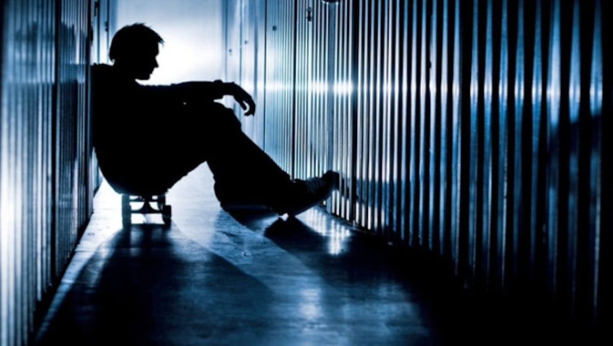 Un jeune homme assis entre des casiers souffre de santé mentale