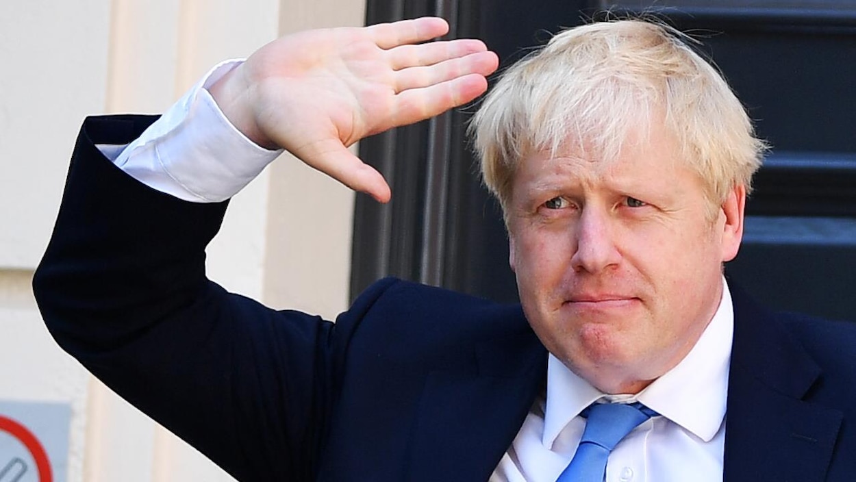 Boris Johnson lève la main en guise de salut.