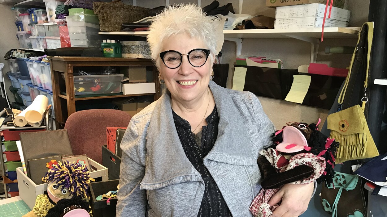 Arlette Gaudet porte une marionette et elle a des lunettes noires.
