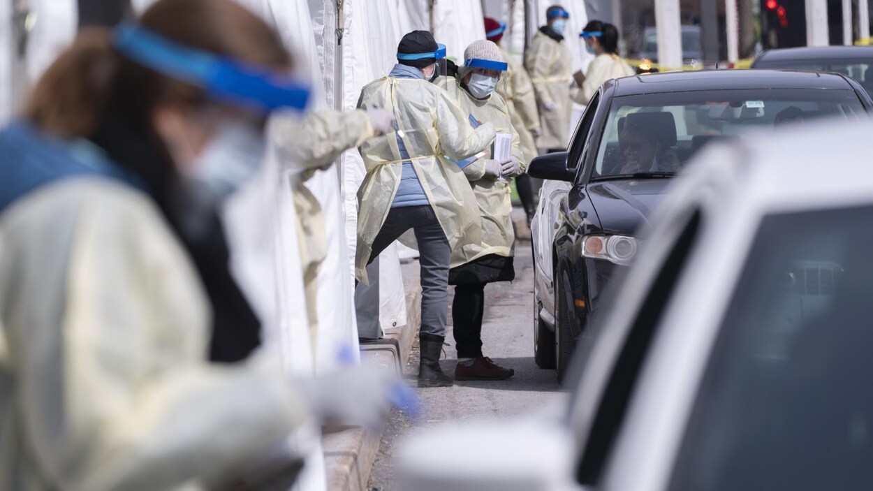 Des travailleurs de la santé effectuent des tests de dépistage de la COVID-19 sur les passagers de voitures dans un service au volant.