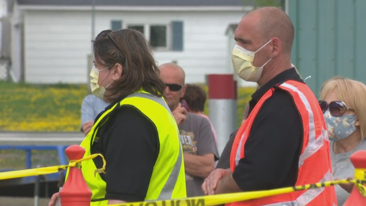 Un homme et une femme portant des masques attendent de subir un test de dépistage de la COVID-19, vendredi à Campbellton.
