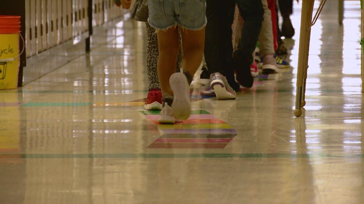 Plan des jambes d'élèves du primaire se déplaçant dans un corridor d'école.