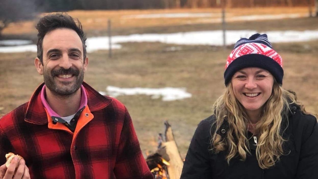 Un homme et une femme assis, main dans la main, devant un champ en début printemps.