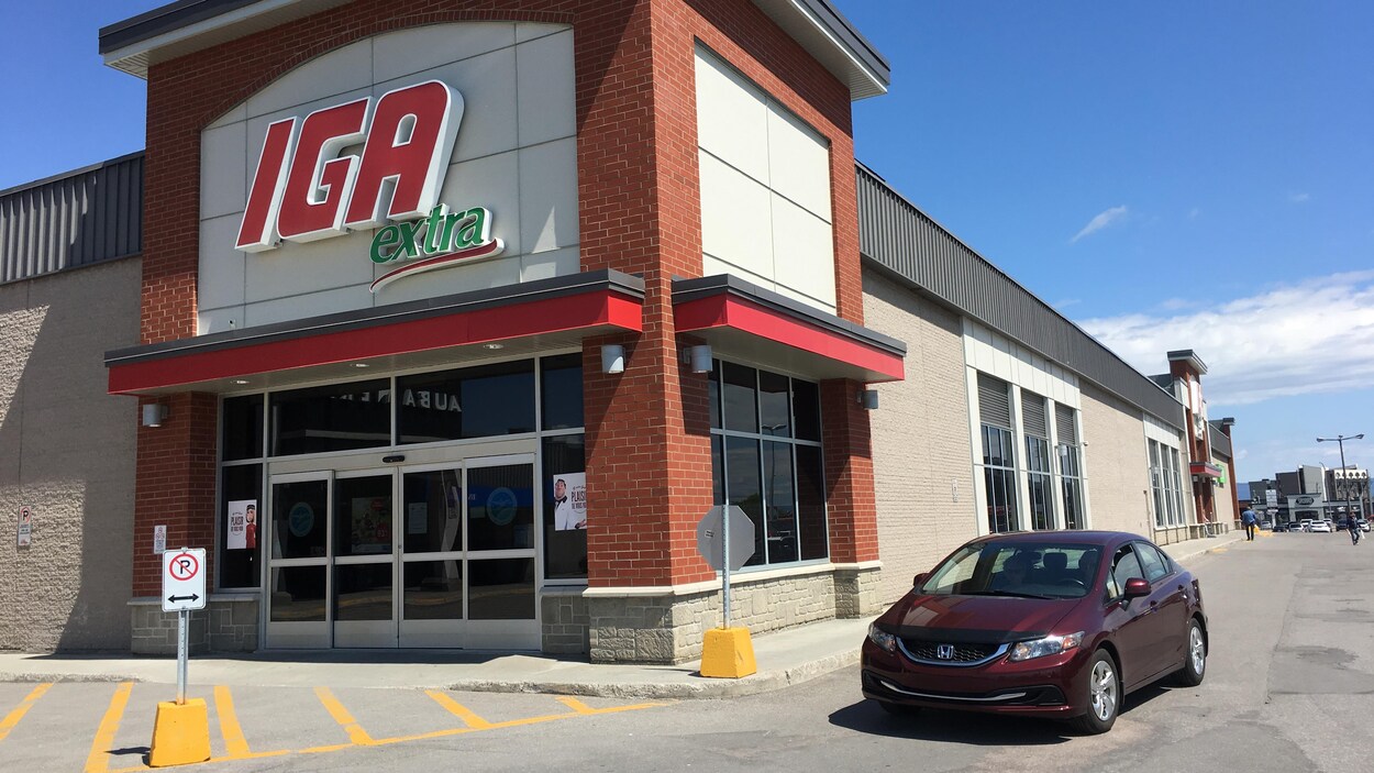 Une voiture est stationnée devant un marché d'alimentation.
