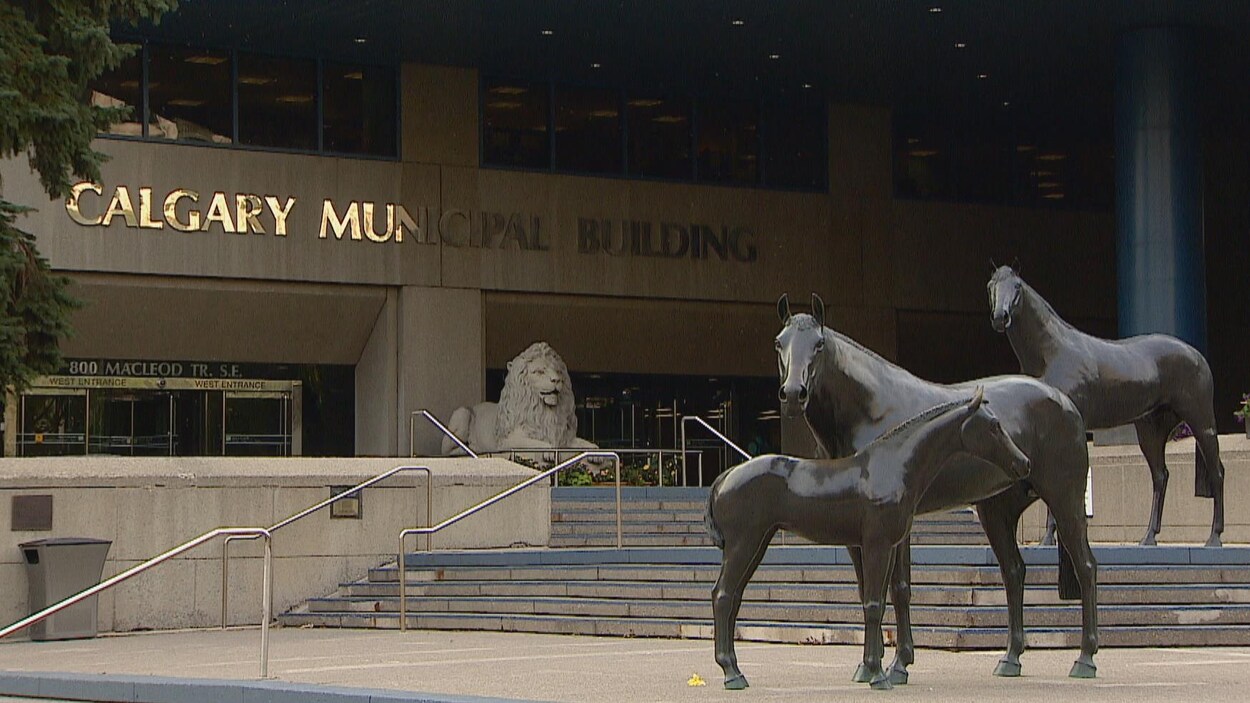 Entrée de l'hôtel de ville de Calgary. Des statues de troix chevaux sont placées sur des marches. Une statue de lion est placée devant les portes d'entrée.