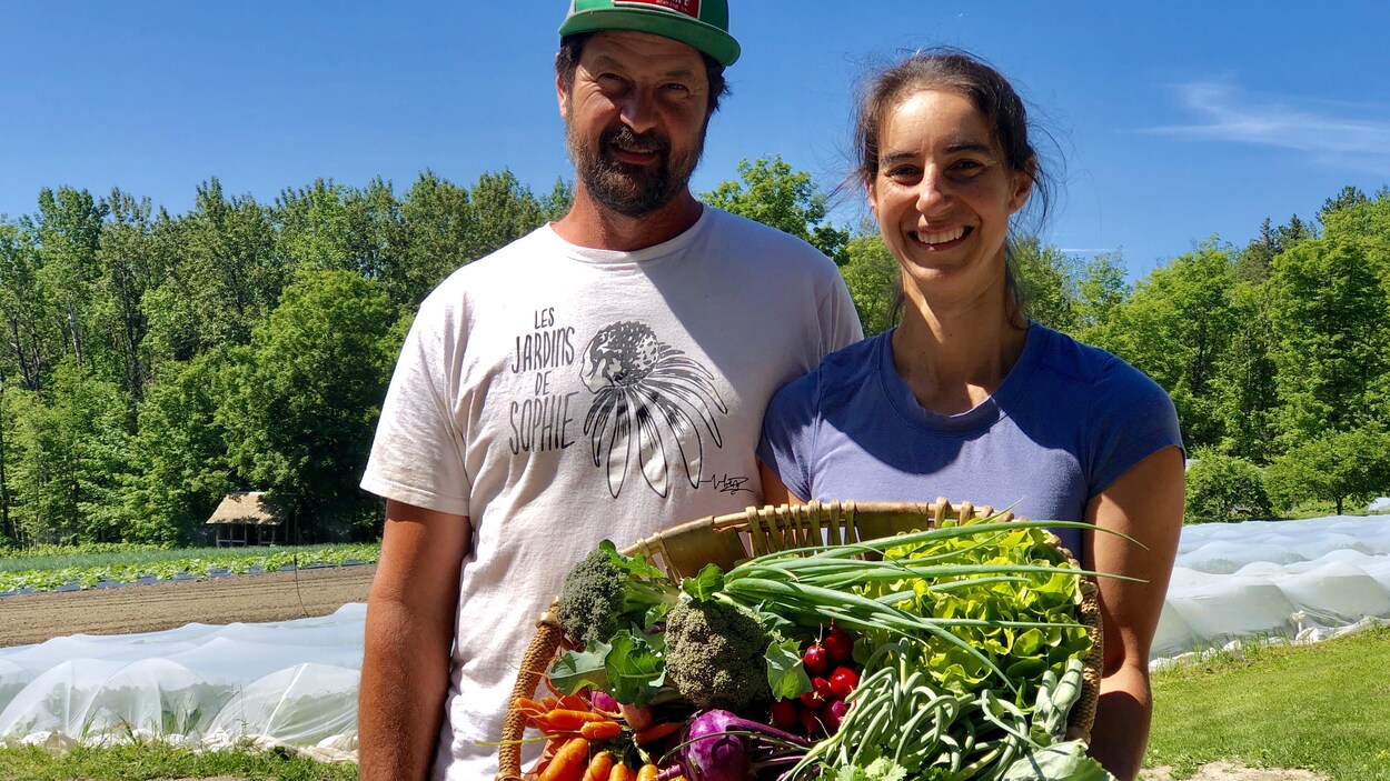 Les propriétaires des Jardins de Sophie tiennent un panier de légumes.
