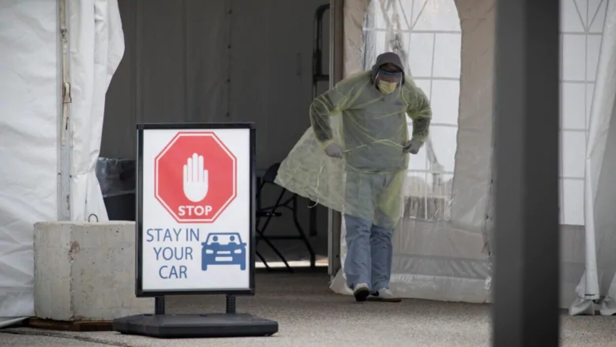 Un travailleur de la santé effectue des tests de COVID-19 au volant, dans une installation spécialement construite près de l'Hôpital général d'Etobicoke, à Toronto.