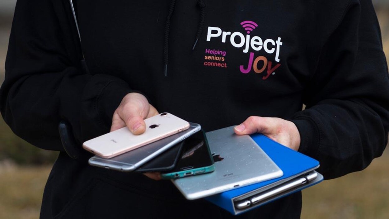 Une femme tient un éventail d'appareils numériques dans ses mains.