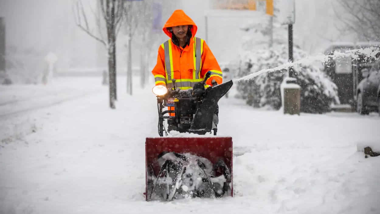 Un homme et sa souffleuse à neige sur le trottoir.
Un homme pousse une souffleuse de neige sur un trottoir du Grand Vancouver très enneigé.