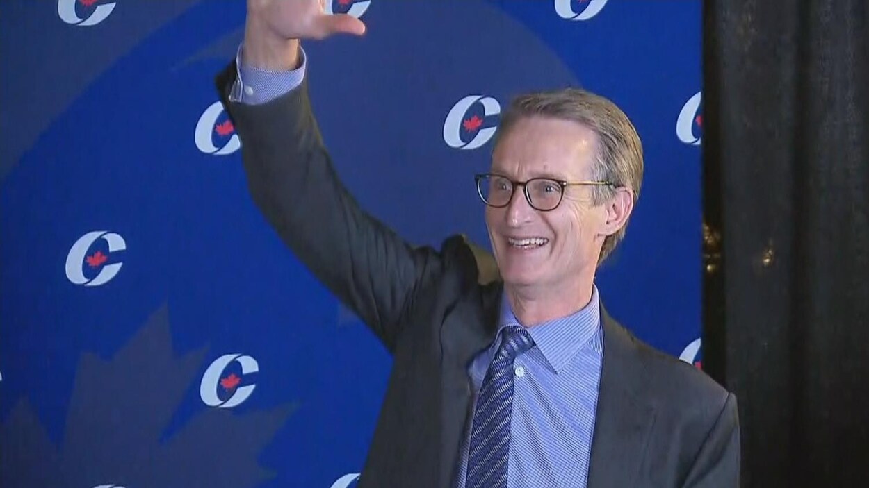 Un homme lève le bras en l'air le sourire aux lèvres.