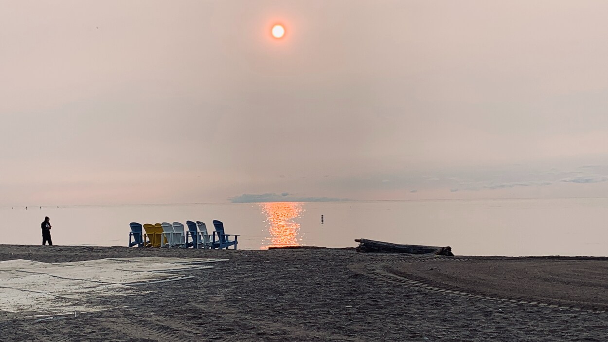 Le soleil paraît orangé dans un ciel couvert par un voile de particules fines.