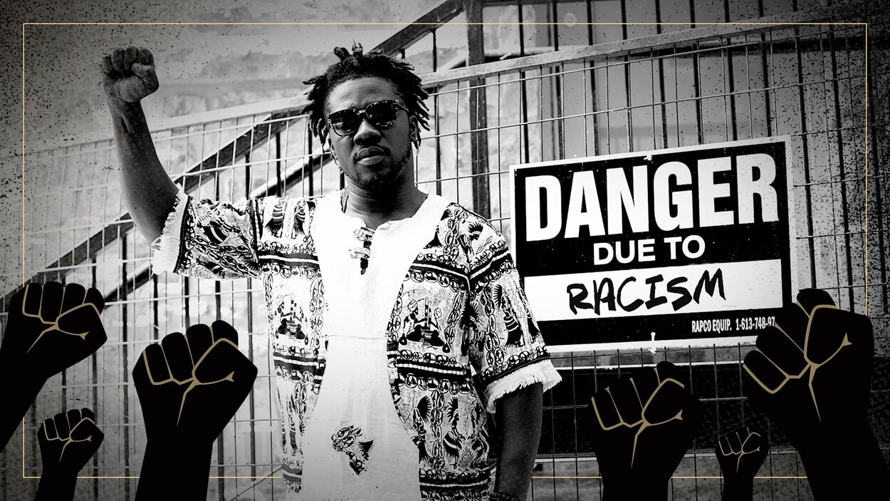 Un homme avec le poing levé aux côtés d'une affiche où est inscrit le message « Danger dû au racisme ».