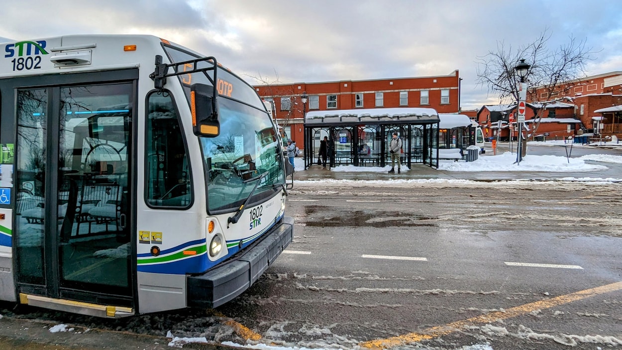 Des autobus de la STTR sont arrêtés au terminus du centre-ville alors que certains usagers attendent l'arrivée d'autres véhicules de transport en commun.