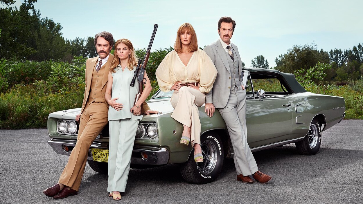 Les quatre personnages sont à côté d'un vieux modèle de voiture.