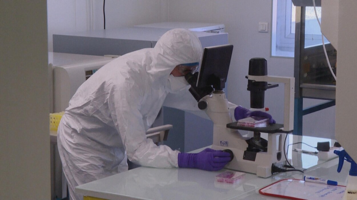 Un homme équipé de protections est penché sur un microscope.