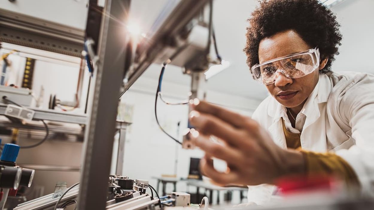 Une femme scientifique travaille sur un appareil technologique.