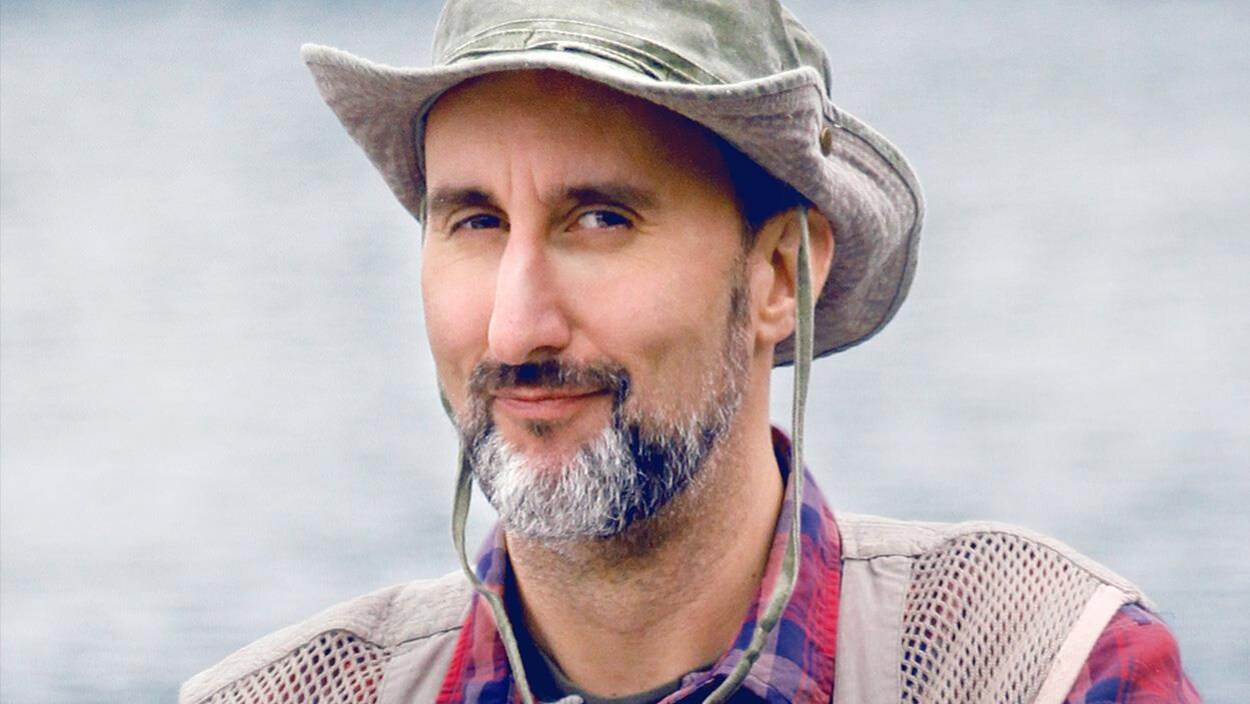 Martin Petit a un chapeau sur la tête et sourit.