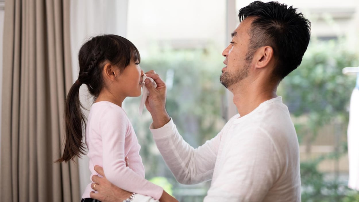 Un père mouche sa petite fille.