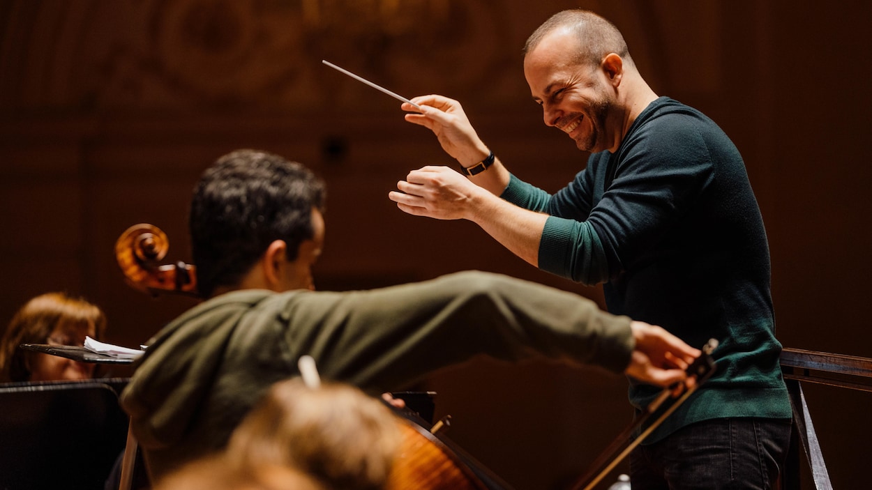 Yannick Nézet-Séguin dirige l'orchestre, le sourire aux lèvres.