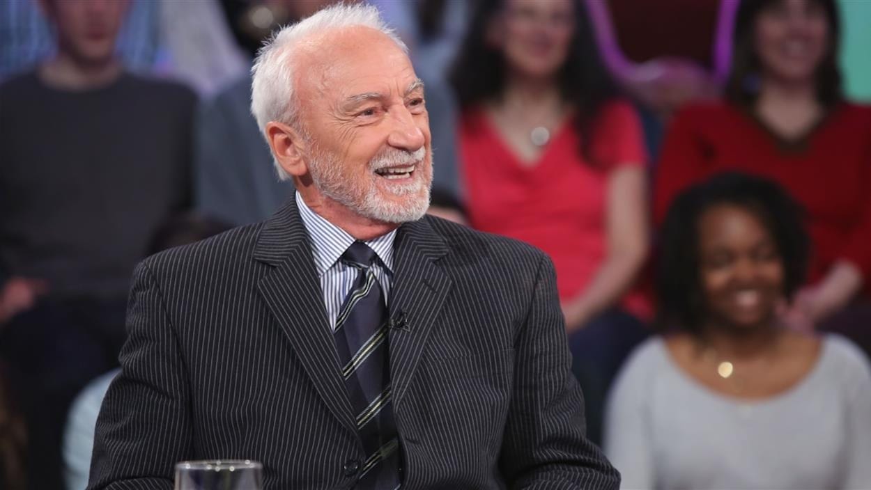 Il porte un habit et une chemise à fines lignes.