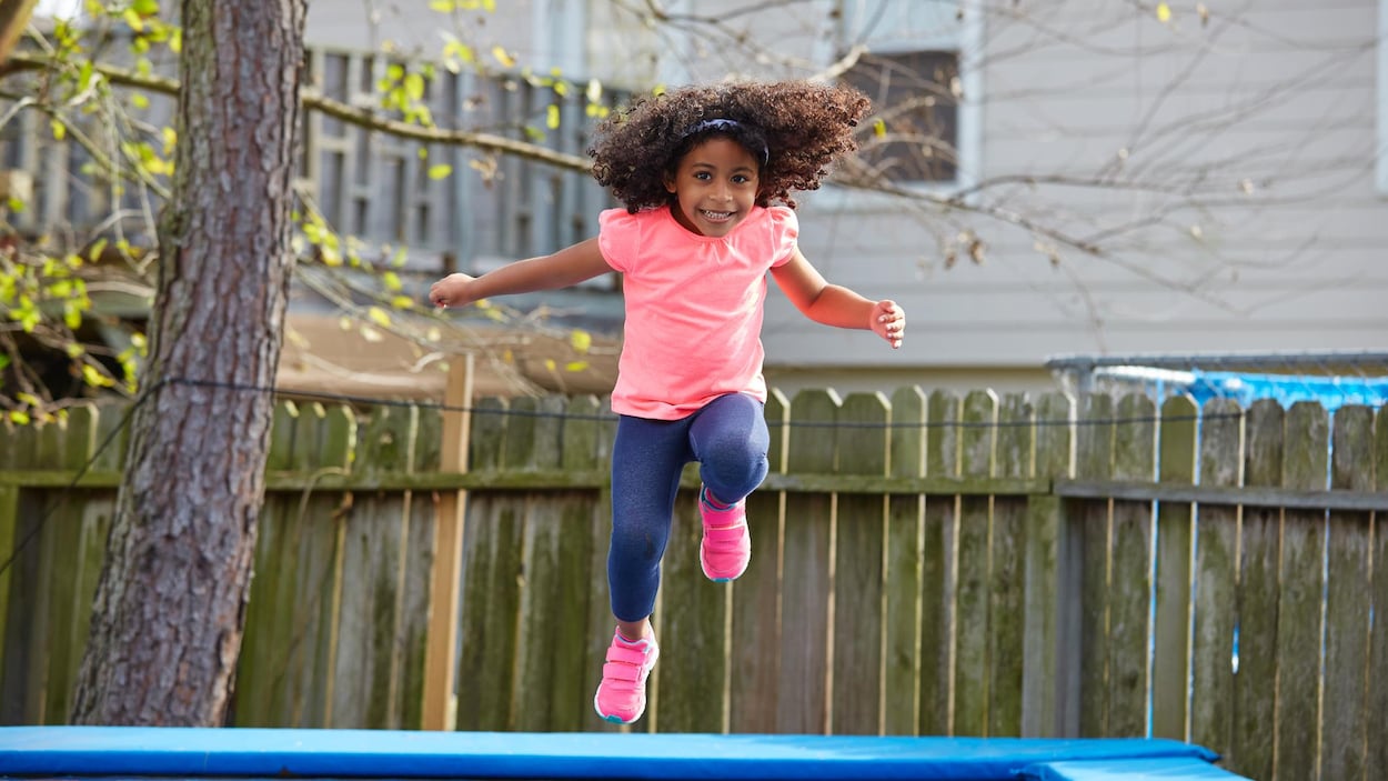 Une jeune fille saute sur un trampoline.