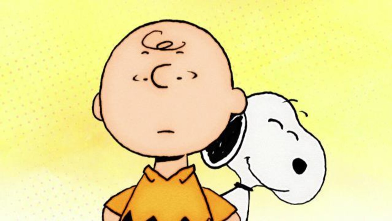 Snoopy se tient derrière Charlie Brown en souriant.