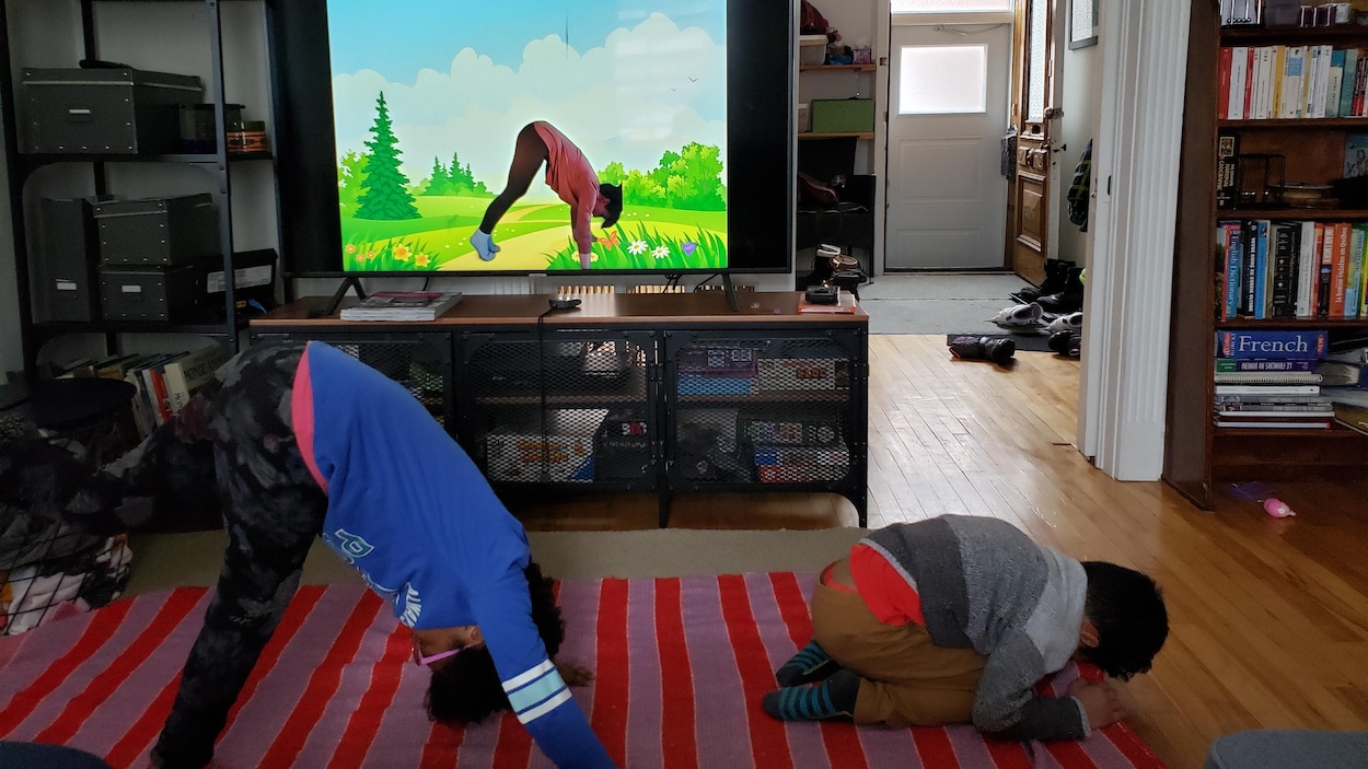 On voit deux petits garçons faire du yoga dans leur salon