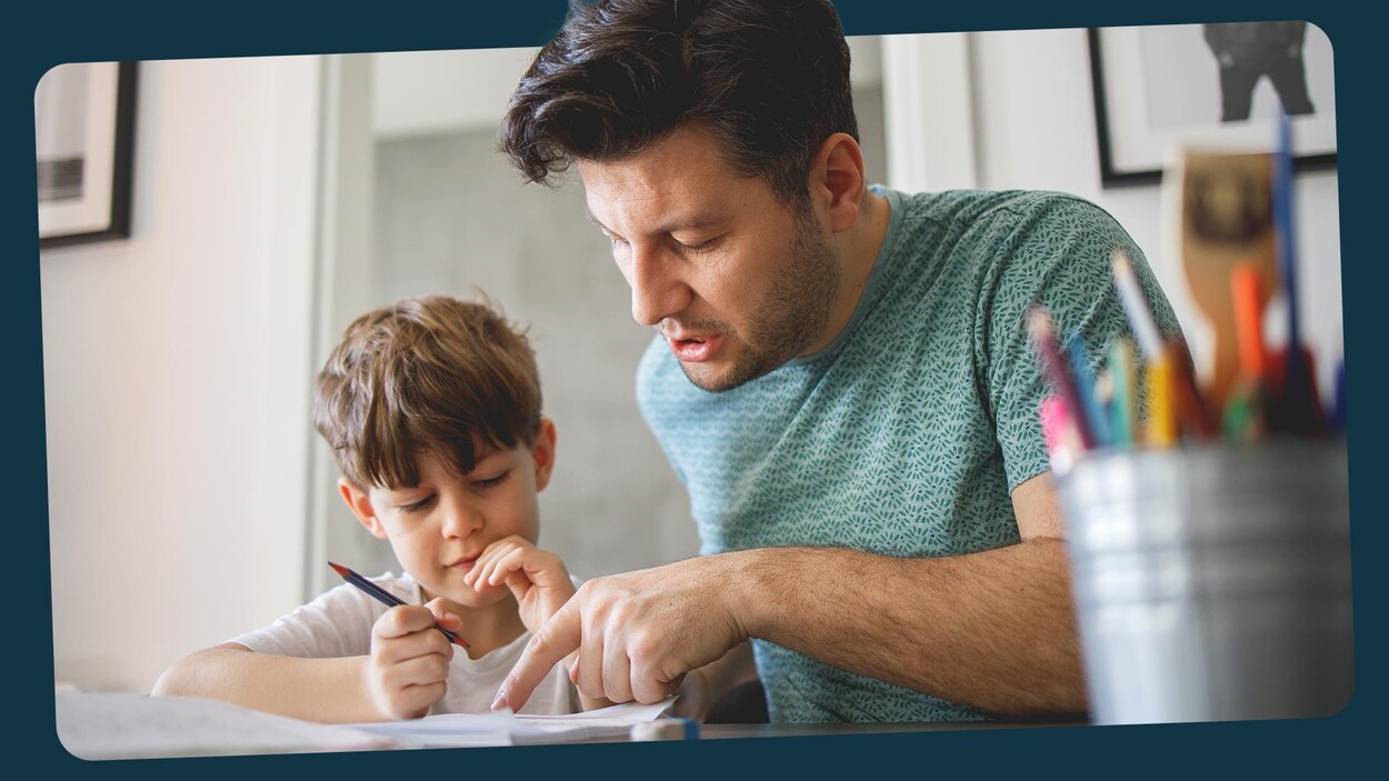 Un papa aide son garçon avec ses devoirs à la maison.