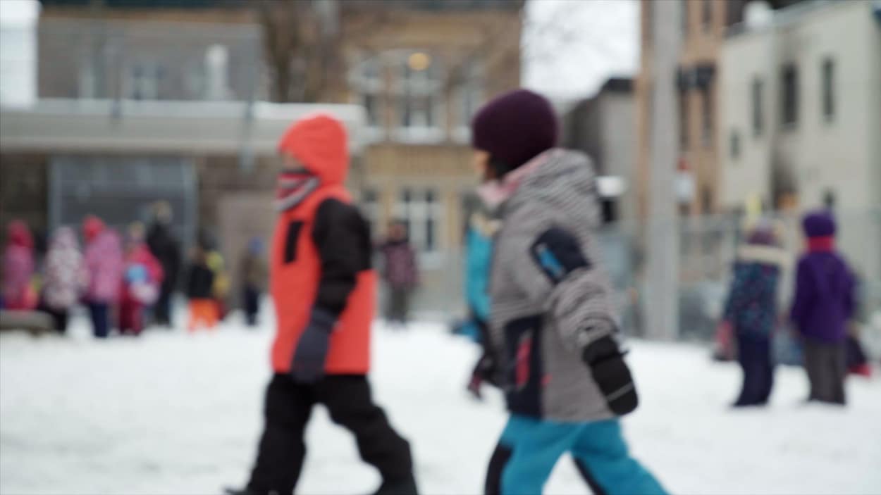 Des enfants dans une cour d'école l'hiver.